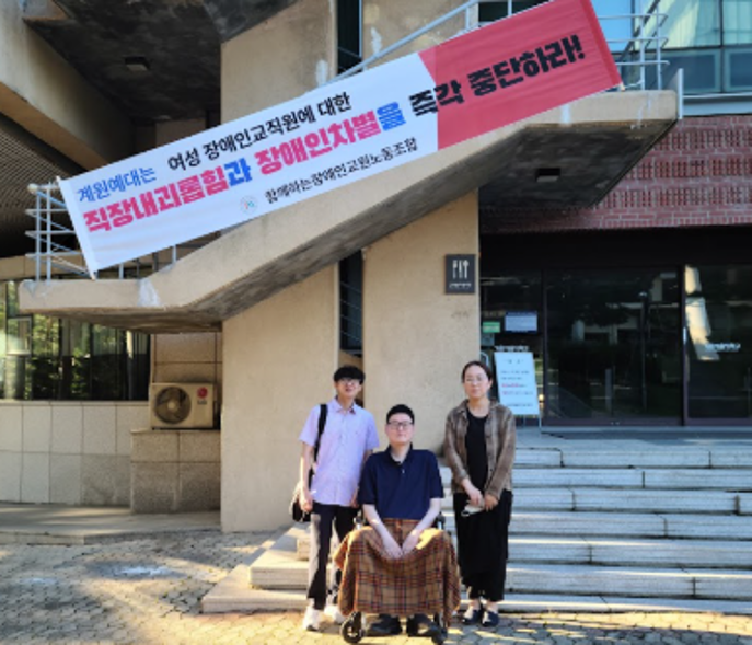 Photo showing protest banner reading 'Stop discrimination against disabled professor' at university entrance